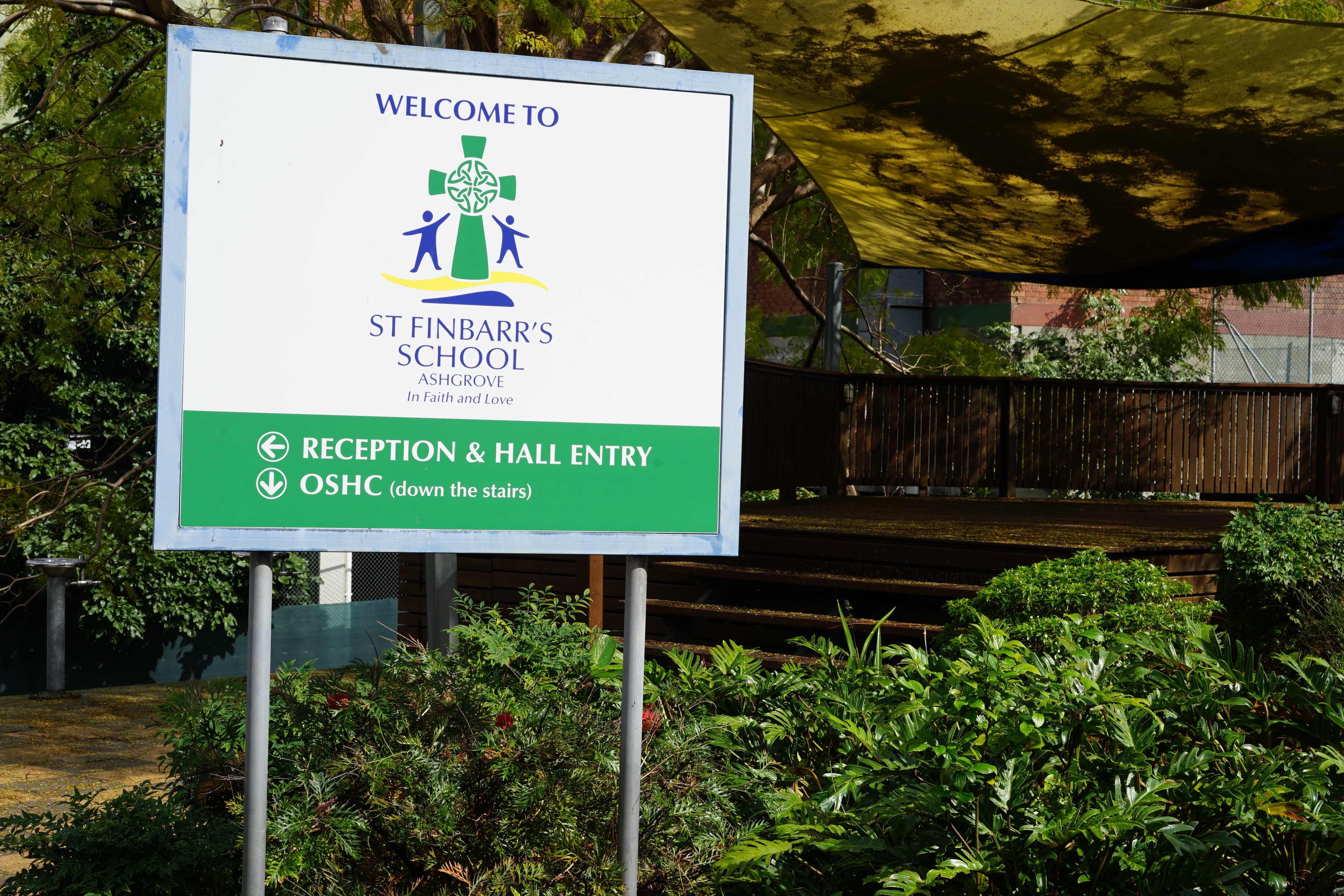 Welcome sign for St Finbarr’s School Ashgrove showing directions to reception, hall entry, and OSHC.