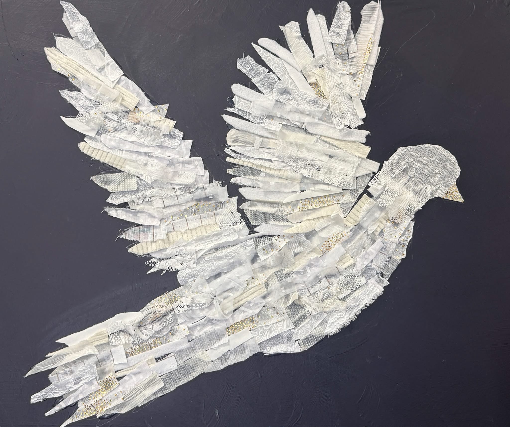 White dove artwork created from layered fabric strips on a dark background.