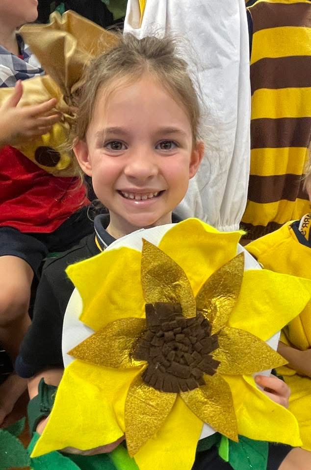 Student holding a sunflower costume at a school event.