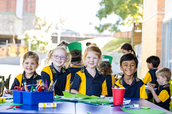 Students working together on a craft activity at outdoor tables.