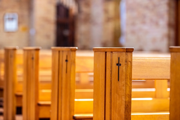 Wooden church pews with a carved cross detail.