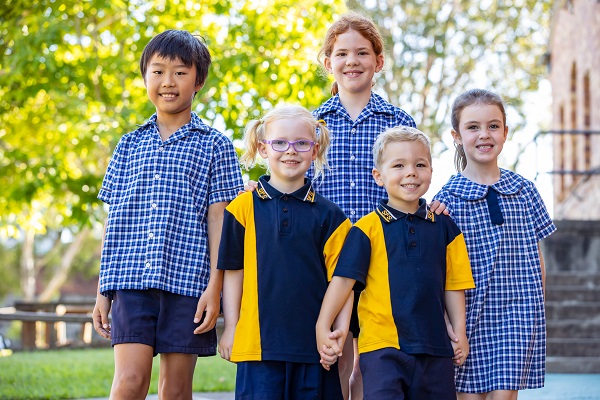 Group of students in school uniform standing together outdoors on school grounds.